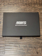 A black rectangular product box with white text reading “.MWS MATCHWORNSHIRT” on the lid, placed on a brown wood-grain surface.